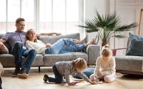 A family relaxing happily at home with the best smart thermostats working to regulate the home temperature.