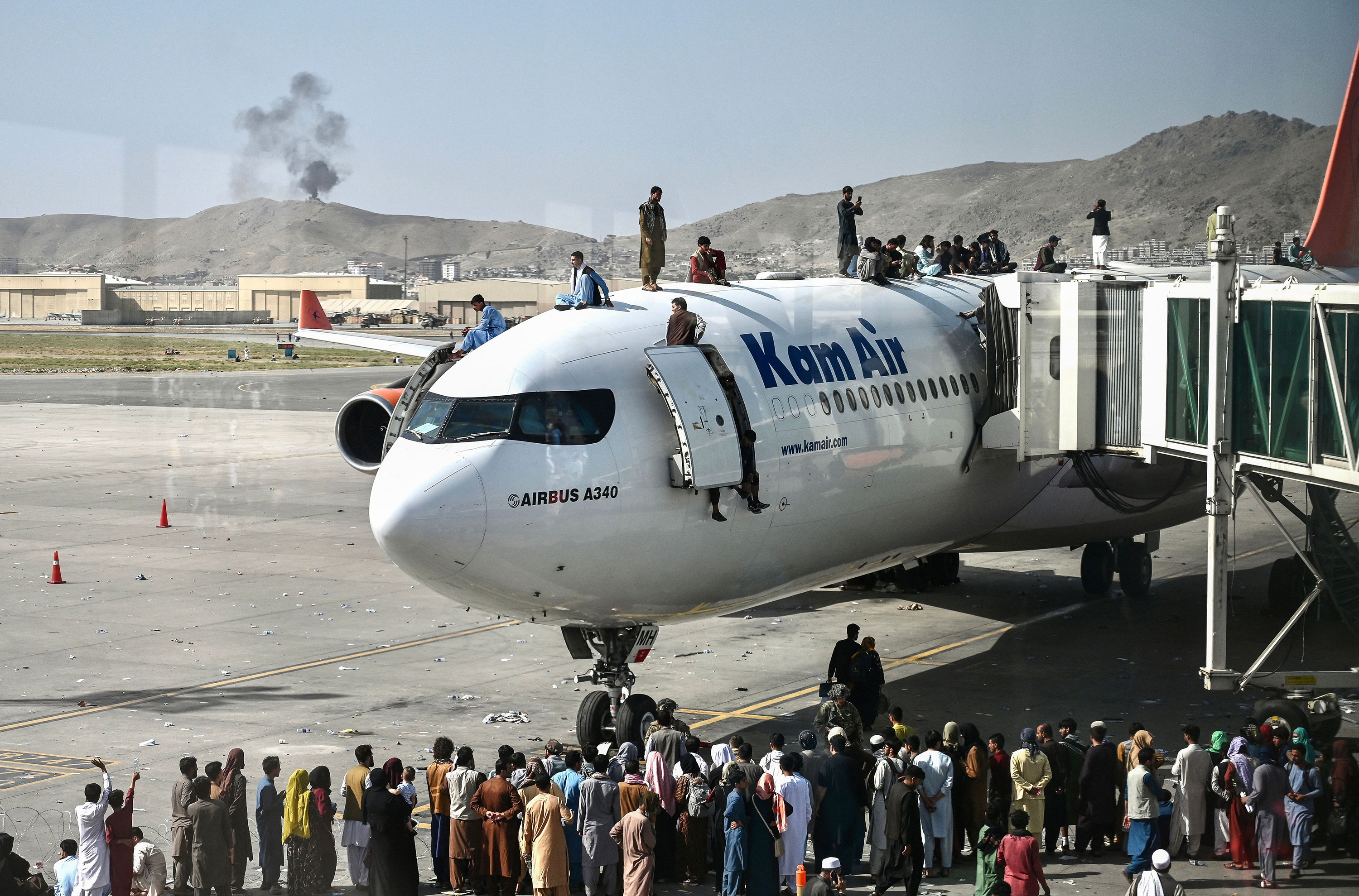 People climb atop a plane at the airport in Kabul on August 16.