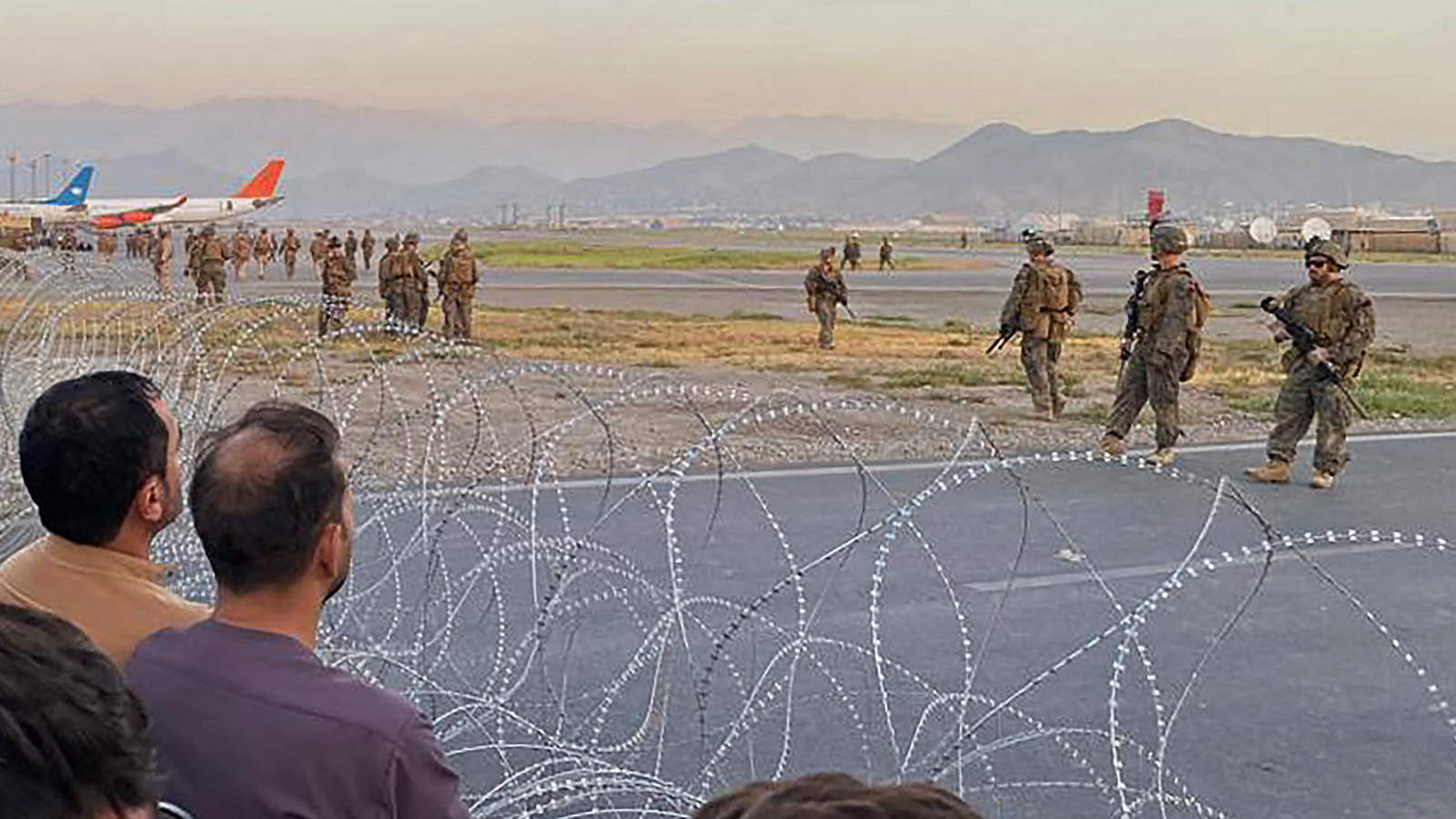 People in Afghanistan crowd at the airport as US soldiers stand guard in Kabul on August 16.