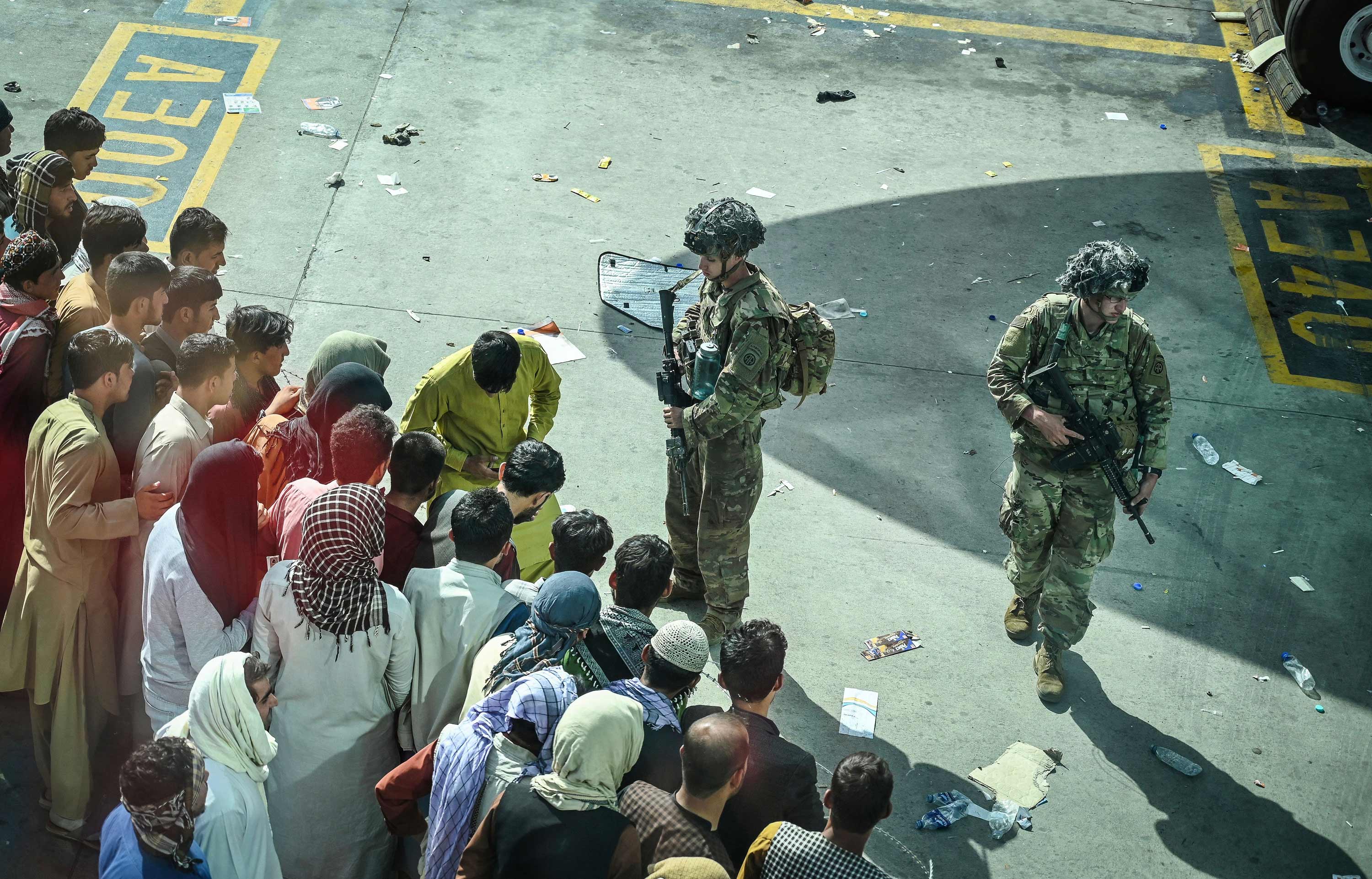 US soldiers stand guard as Afghan people wait at the Kabul airport on August 16.