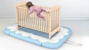 An image of a baby with a safety mat highlighting the dangers of a baby climbing and falling out of a crib withou a safety mat.