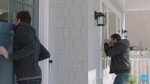 A criminal peeping through a window and is caught by a doorbell security camera.
